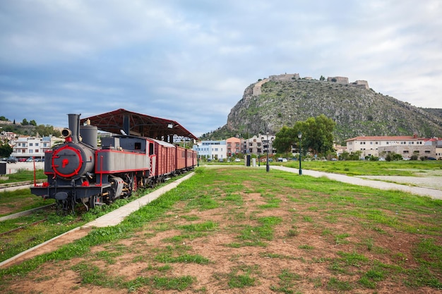 Antiguo tren en la estación de tren de Nafplio y la fortaleza de Palamidi en la montaña en Nafplio, Grecia