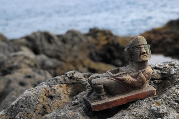 Antike Maya-Statue auf den Felsen in der Nähe des Ozeans