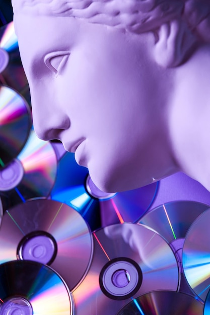 Antike Statue der Venuskopfnahaufnahme vor dem Hintergrund von Glitzer-CDs. Konzept von Musik, Stil, Vintage. Getönt.