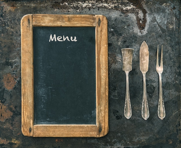 Antikes Silberbesteck und Tafel mit Beispieltext Menü. Getöntes Bild im Vintage-Stil. Food-Konzept