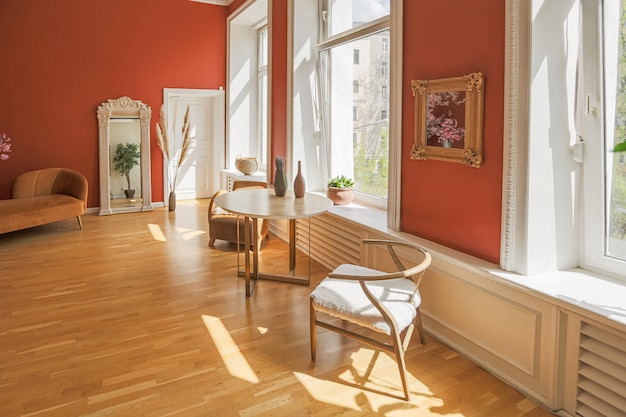 Antikes Vintage-Interieur im Wohnzimmer im Stil des 19. Jahrhunderts mit leuchtend roten Wänden, Holzboden und direktem Sonnenlicht im Zimmer.