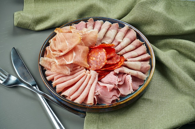 Antipasti de carne italiana de lujo para vino en plato de cerámica sobre superficie de madera. salami, jamón, jamón serrano y chorizo. De cerca, enfoque selectivo.