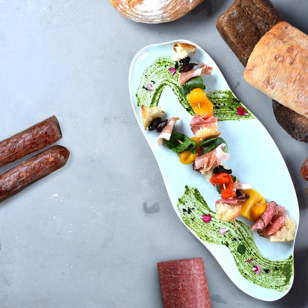 Foto antipasti italienisches gericht. vorspeise mit fleisch, gemüse und kräutern auf einem grauen tisch
