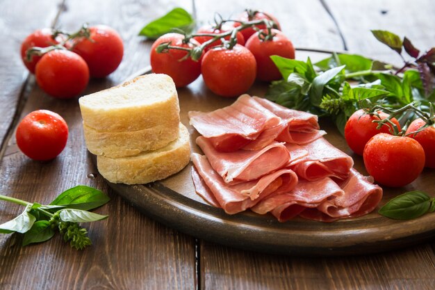 Antipasto com presunto e bresaola. tomate e manjericão. foco seletivo