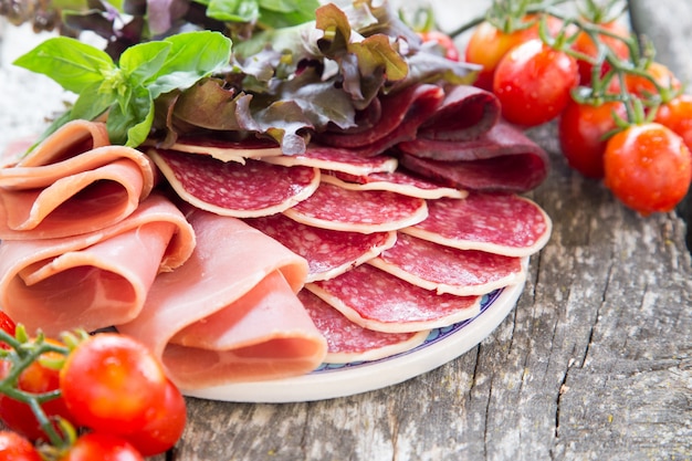 Antipasto con jamón, salami y bresaola. Tomate y albahaca. enfoque selectivo