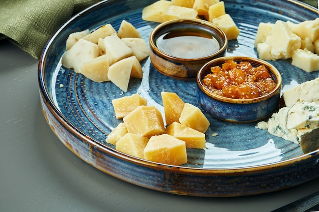 Antipasto - um prato de queijo. queijos caseiros diferentes em um prato de cerâmica - brie, camembert, holandês com mel e nozes. aperitivo de vinho. feche acima, foco seletivo