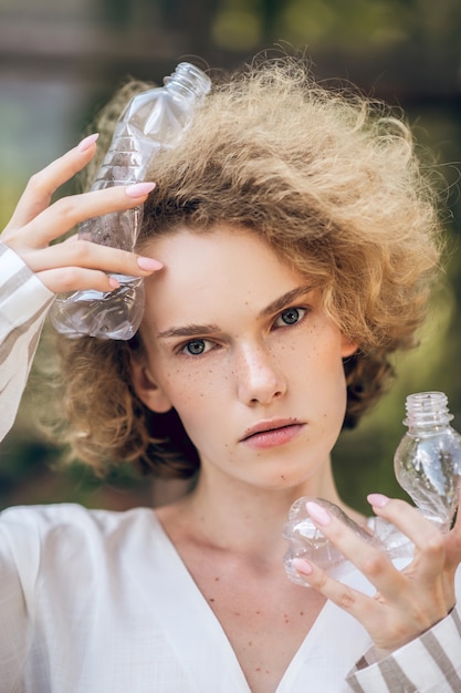 Antiplastische Kampagne. Blondhaarige Frau, die Plastikflaschen in den Händen hält