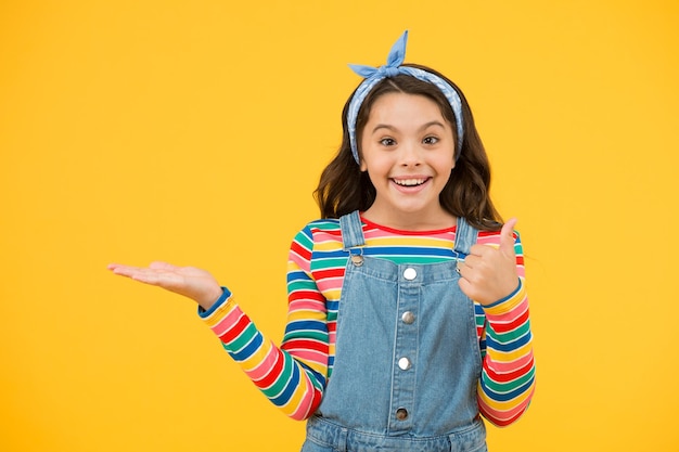 Antiquado criança moda pequena beleza lenço cabelo longo estilo vintage feliz infância retrô menina alegre gesto verão férias alegria criança pequena fundo amarelo apresentando produto
