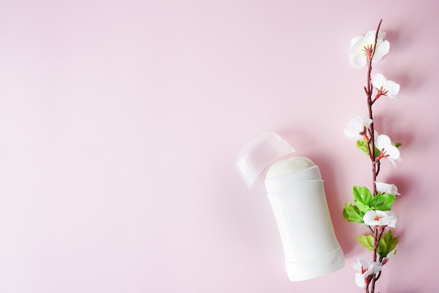 Antitranspirant oder Deodorant mit weißen Blumen auf rosa Hintergrund. kopieren sie platz