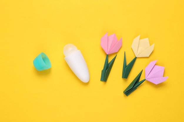 Antitranspirant-Stick und Origami-Tulpen auf gelbem Hintergrund