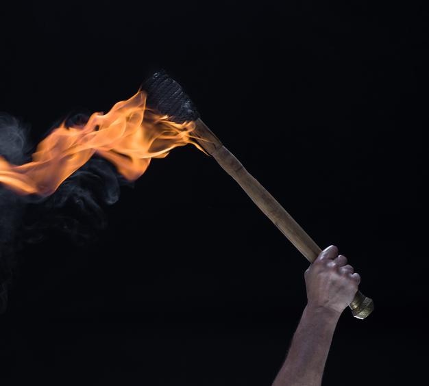 una antorcha de madera ardiente en la mano aislada sobre un fondo negro