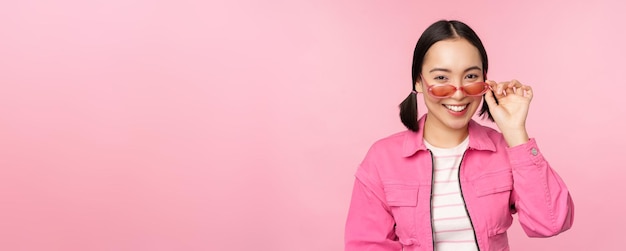 Anuncio de gafas Elegante chica asiática moderna toca gafas de sol usa poses rosas contra el fondo del estudio Copiar espacio