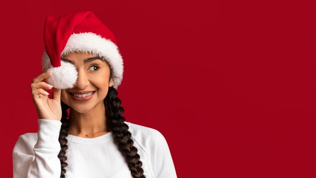 Anuncio de Navidad Dama árabe alegre con sombrero de Santa que cubre los ojos con pompón