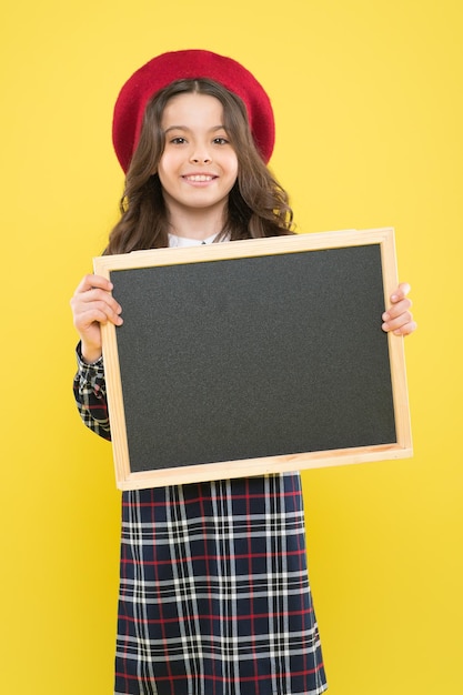 Anúncio ou promoção Anúncio de evento Fico feliz em informá-lo Criança feliz com quadro promocional Local para anúncio ou anúncio Menina com sorriso segura quadro-negro em branco Espaço de cópia de produto publicitário