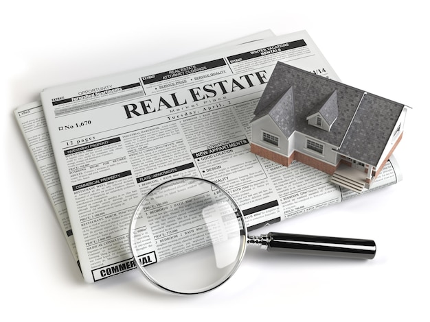 Anuncios clasificados de bienes raíces periódico con casa y lupa aislado en blanco