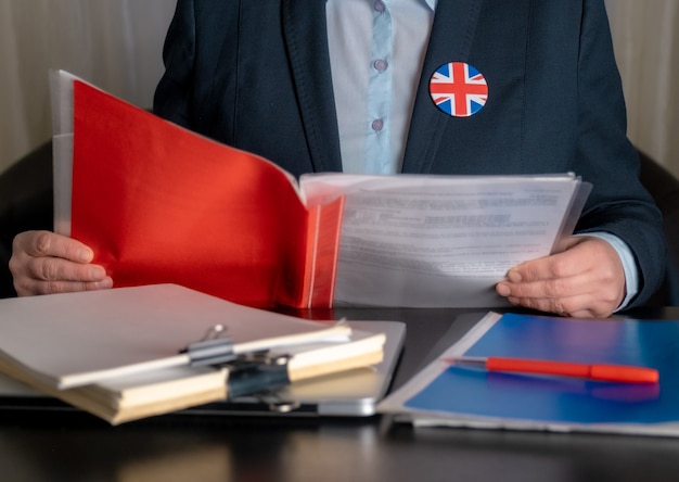 Anwalt oder Büroangestellter oder Beamter in der Nähe seines Arbeitsplatzes mit der Flagge Großbritanniens auf einem Jackensymbol