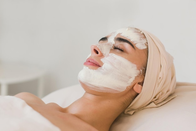 Anwendung einer Spa-Gesichtsmaske. Spa-Beauty-Bio-Gesichtsmaskenanwendung im Day-Spa-Salon. Frau, die Gesichtslehmmaske im Spa-Salon anwendet, Hautpflege, Draufsicht.