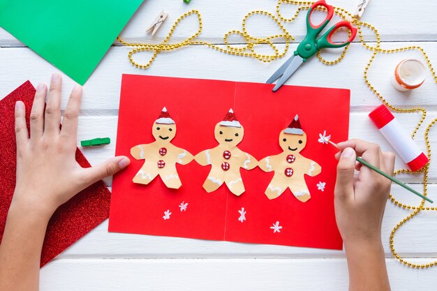 Foto anwendung für kinder. weihnachts- oder neujahrskarte mit lebkuchenmann aus papier. heimwerken. anweisungen.