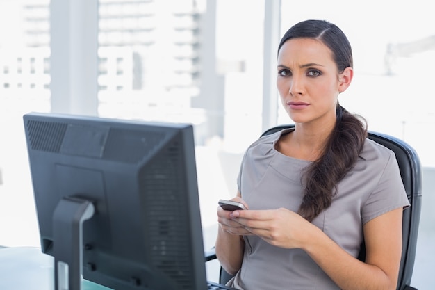 Anxious dark haired businesswoman sending message