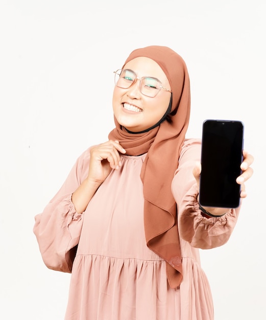 Anzeigen von Apps auf dem Smartphone mit leerem Bildschirm einer schönen asiatischen Frau, die Hijab trägt, isoliert auf Weiß