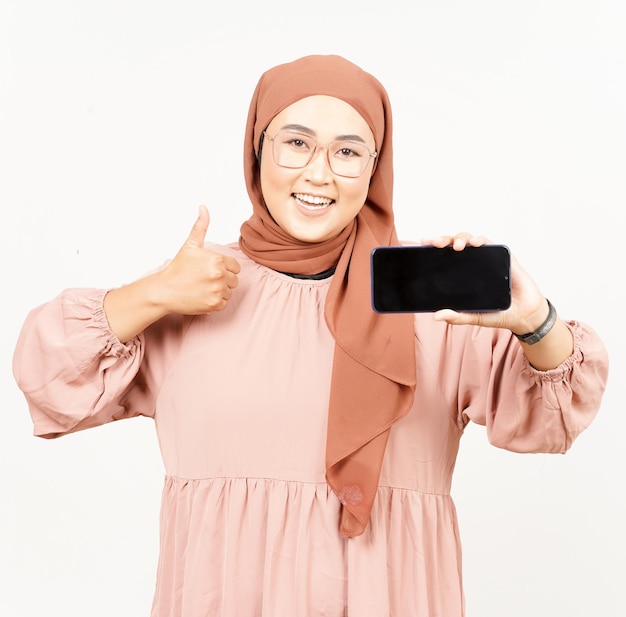 Anzeigen von Apps auf dem Smartphone mit leerem Bildschirm einer schönen asiatischen Frau, die Hijab trägt, isoliert auf Weiß