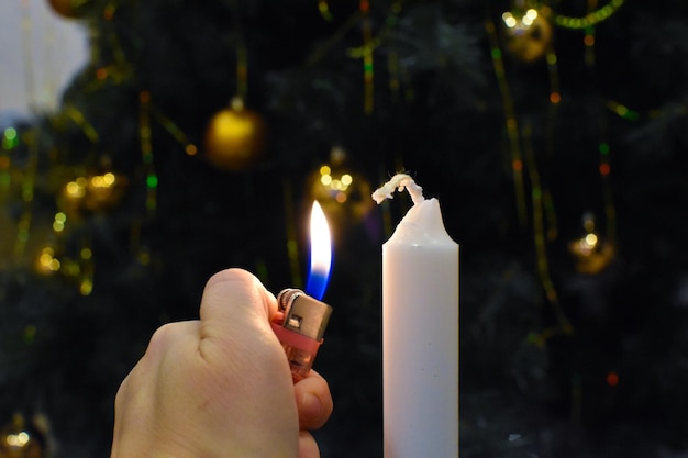 Anzünden einer Kerze mit einem Feuerzeug. brennende Kerze im Dunkeln