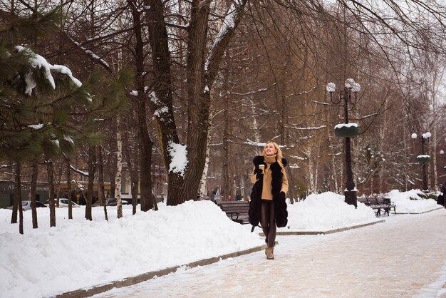 Ao ar livre feche a foto da mulher sorridente feliz bonita andando na rua no inverno.