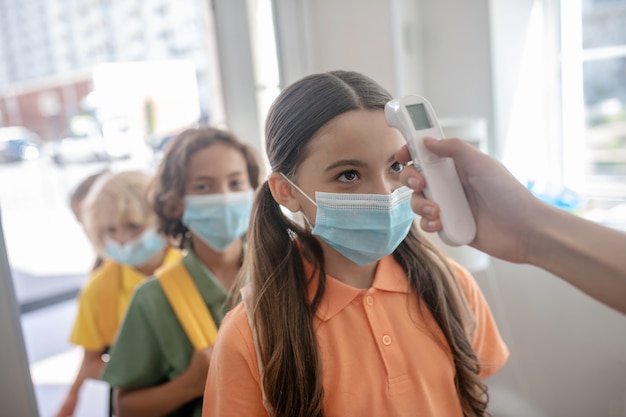 Foto ao controle. crianças passando no controle de temperatura ao entrar na escola