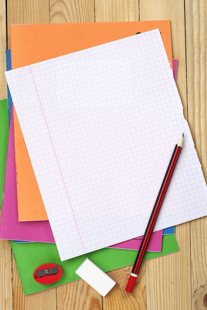 Foto apagador de lápis de livros de exercícios multicoloridos e folha em branco na mesa