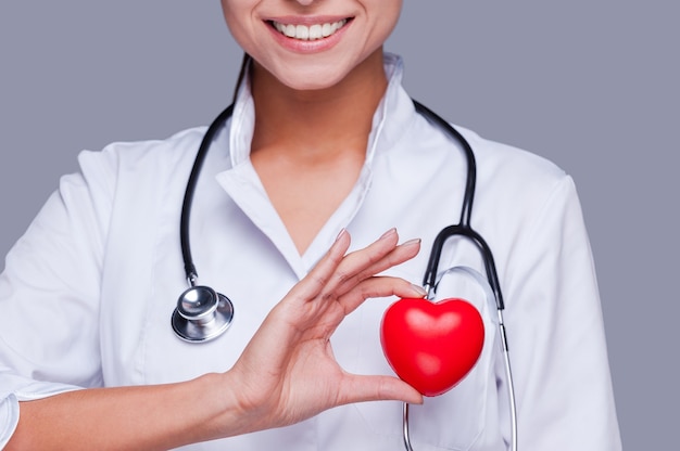 Apaixonado por sua profissão. close de uma médica de uniforme branco segurando um suporte de coração