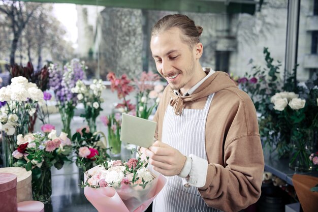 Apaixonar-se. Homem gentil expressando positividade enquanto trabalhava em uma floricultura