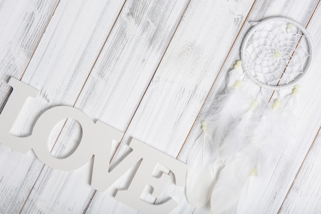 Apanhador de sonhos branco e texto de amor na mesa de madeira, plana leigos