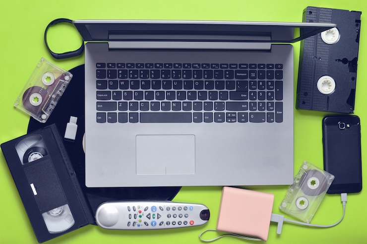 Foto aparatos digitales modernos, medios de almacenamiento y dispositivos de medios analógicos obsoletos en una superficie de papel verde
