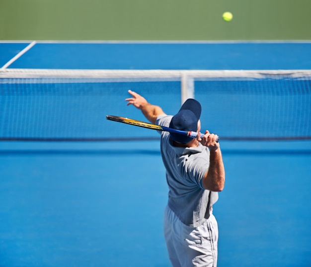 Aparecendo em todos os treinos de tênis Foto de um homem tentando devolver uma bola em uma quadra de tênis