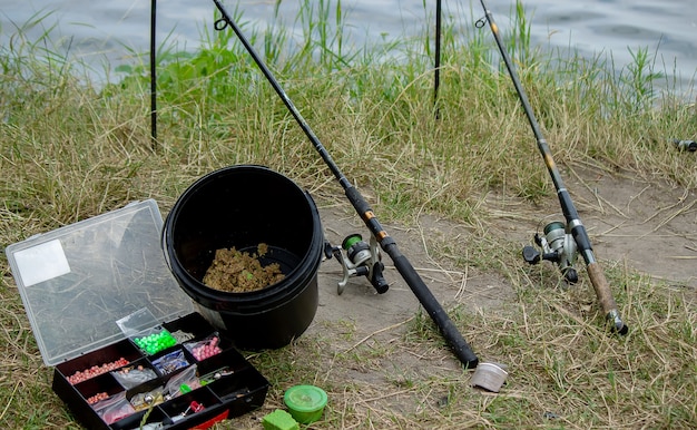 Aparejos de pesca en la orilla del río, caña de cebo, caña de spinning, pescado. Naturaleza. Enfoque selectivo