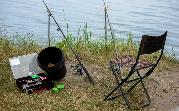 Aparejos de pesca en la orilla del río, caña de cebo, caña de spinning, pescado. Naturaleza. Enfoque selectivo