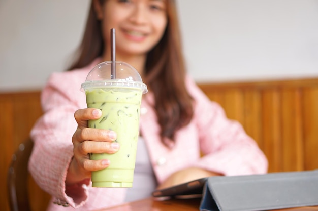 Aparelho de mulher asiática assiste computador Bebe chá verde para refrescar