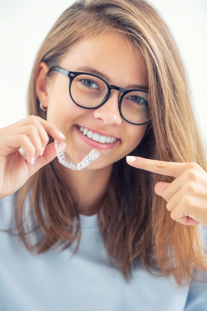 Foto aparelho dentário invisível ou treinador de silicone nas mãos de uma jovem sorridente. conceito ortodôntico - invisalign.