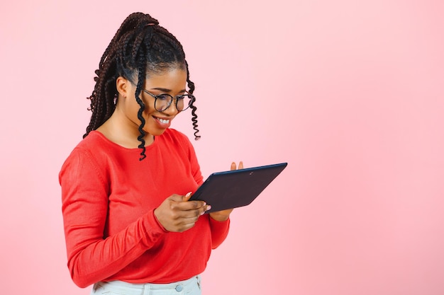 Aparelho legal. Garota interessada usando tablet digital em fundo rosa