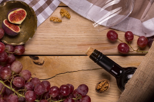 Apartamento com uma tempestade de uvas vermelhas, uma garrafa de vinho, um copo e figos