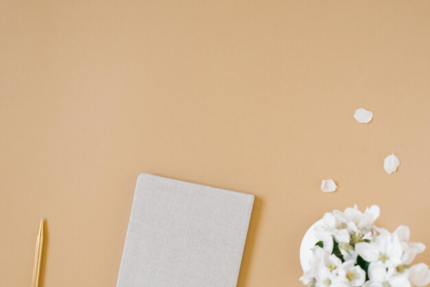 El apartamento de concepto de trabajo desde el hogar yacía sobre una mesa beige con un bolígrafo y un jarrón de flores