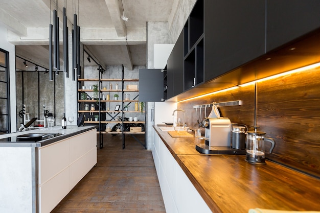 Apartamento de luxo em estilo loft em cores escuras. Cozinha moderna com ilha