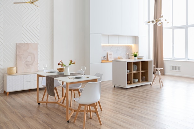 Apartamento espaçoso e luminoso com design de interiores em estilo escandinavo e tons pastel de branco e bege. Móveis modernos na área de estar e detalhes modernos na área da cozinha.
