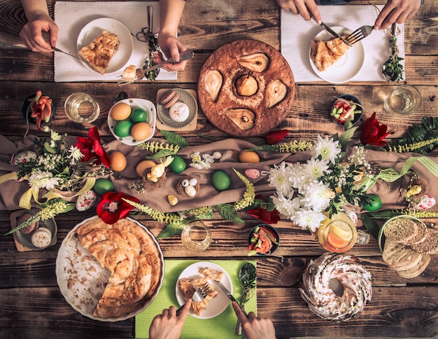 Apartamento-fiesta de amigos o familiares en la mesa festiva con carne de conejo, verduras, pasteles, huevos, vista desde arriba.