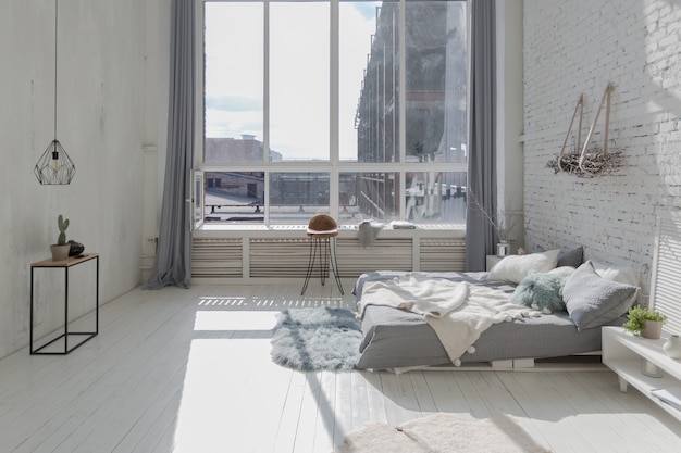 Apartamento loft espaçoso, elegante e moderno, nas cores branco e cinza cheio de luz solar. parede de alvenaria, estantes, estrado e casinha infantil em forma de tenda.