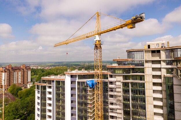 Apartment oder büro hohes gebäude im bau. backsteinmauern, glasfenster, gerüste und betonstützpfeiler. turmkran auf hellblauem himmel kopieren raum