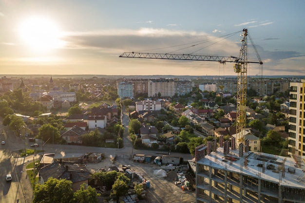 Apartment oder Büro hohes Gebäude im Bau. Backsteinmauern, Glasfenster, Gerüste und Betonstützpfeiler. Turmkran auf hellblauem Himmel kopieren Raum