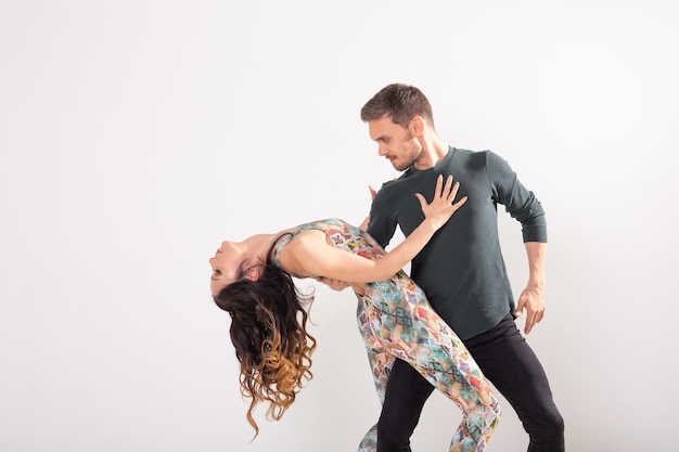 Apasionada pareja bailando un baile latino en la pared blanca