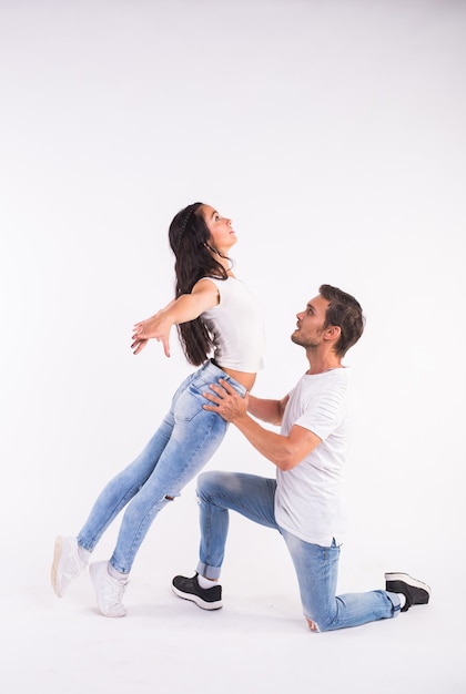 Apasionada pareja bailando danza social kizomba o bachata o semba o taraxia sobre fondo blanco.