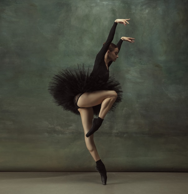 Apasionado. Elegante bailarina clásica bailando, posando aislado en la pared oscura del estudio